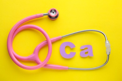 Stethoscope and calcium symbol made of purple letters on yellow background, flat lay