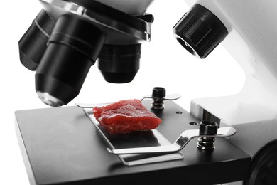 Photo of Piece of raw cultured meat under microscope on white background, closeup