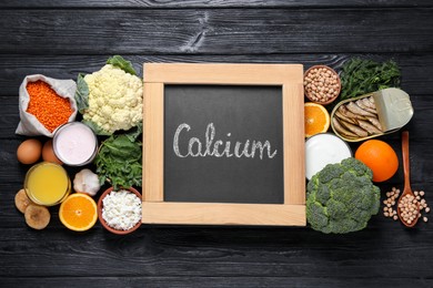 Set of natural food and chalkboard with written word Calcium on black wooden table, flat lay