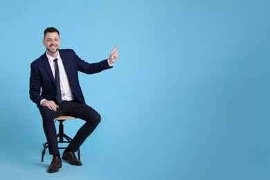 Handsome businessman sitting in office chair on light blue background