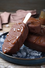 Photo of Delicious glazed ice cream bars and ice cubes on wooden table, closeup