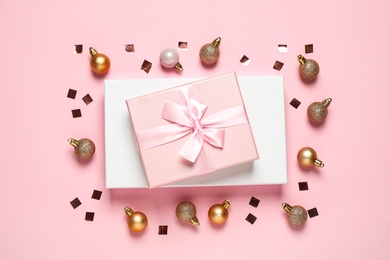 Photo of Beautiful gift boxes, golden Christmas balls and confetti on pink background, flat lay