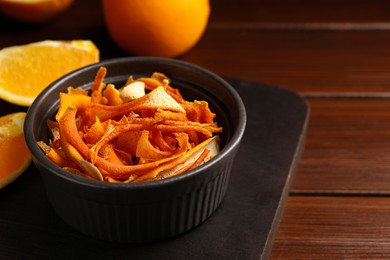 Photo of Bowl with dry orange peels and fresh fruits on wooden table, closeup