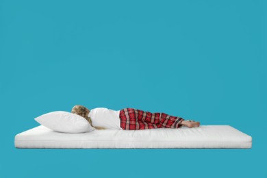 Photo of Little girl sleeping on comfortable mattress against light blue background, space for text