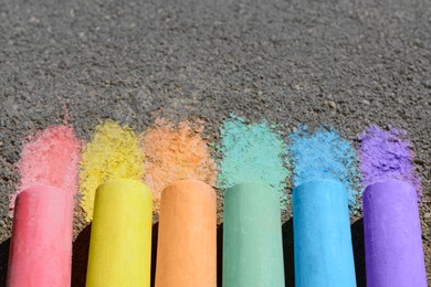 Colorful chalk sticks on asphalt outdoors, closeup. Space for text