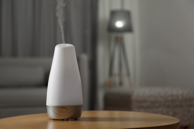 Aroma oil diffuser on wooden table indoors, space for text. Air freshener