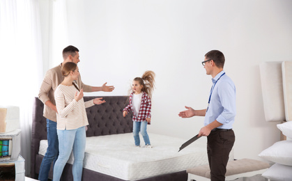 Photo of Salesman showing family mattress in furniture store