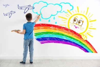 Cute child boy drawing of colorful dye on white wall indoors