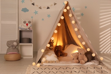 Photo of Modern children's room interior with play tent and lights