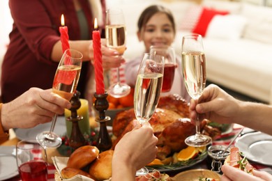 Family clinking glasses of drinks at festive dinner, focus on hands. Christmas celebration