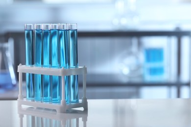 Test tubes with light blue liquid on table in laboratory. Space for text