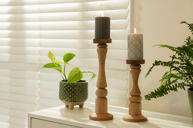 Photo of Pair of beautiful wooden candlesticks and houseplants on white table