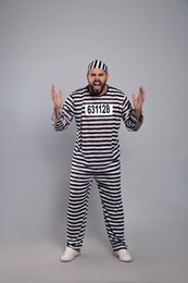 Emotional prisoner in special uniform on grey background