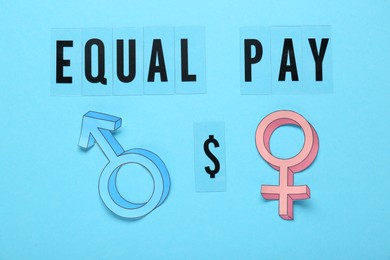 Photo of Equal pay concept. Gender symbols on light blue background, flat lay