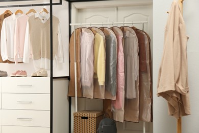 Garment bags with clothes on rack in dressing room
