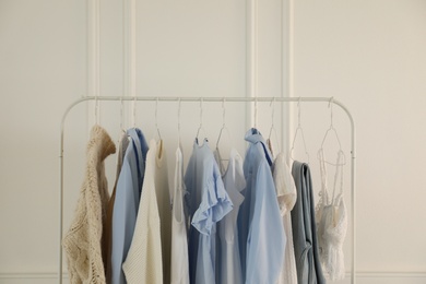 Rack with stylish women's clothes near white wall. Interior design