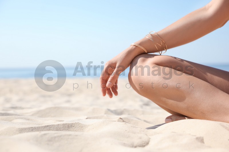Young woman with beautiful body on sandy beach, closeup. Space for text