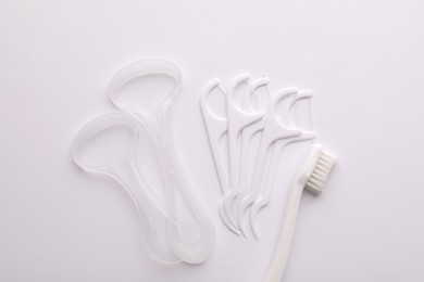 Tongue cleaners, dental floss picks and toothbrush on white background, top view