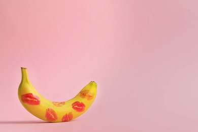 Banana covered with red lipstick marks on light pink background, space for text. Potency concept