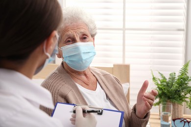 Photo of Doctor examining senior woman with protective mask at nursing home