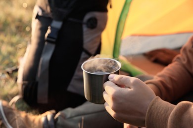 Man with cup of hot drink in camping tent, closeup