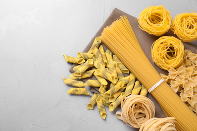Different types of pasta on light grey table, flat lay