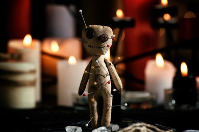 Voodoo doll pierced with pins on table in dark room. Curse ceremony