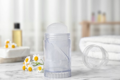 Natural crystal alum deodorant and chamomile flowers on white marble background