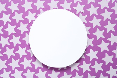 White star shaped confetti and blank card on violet background, flat lay. Space for text