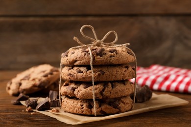 Many delicious chocolate chip cookies on wooden table