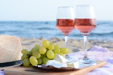 Glasses with rose wine and snacks for beach picnic on sandy seashore
