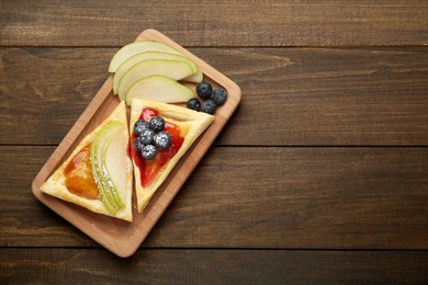 Photo of Fresh tasty puff pastry with jam, blueberries and pear on wooden table, top view. Space for text