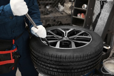 Technician working with car wheel at automobile repair shop, closeup