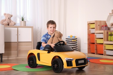 Little child with bunny driving toy car in room