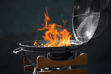 New modern barbecue grill with burning firewood on dark background