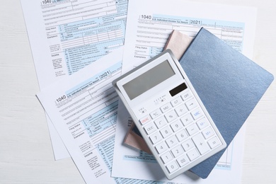 Calculator, notebooks and documents on white table, flat lay. Tax accounting