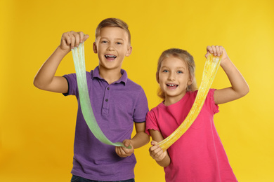 Photo of Happy children with slime on yellow background