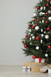 Beautifully decorated Christmas tree and many gift boxes in room, space for text