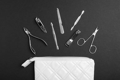 Photo of Set of manicure tools and bag on black background, flat lay