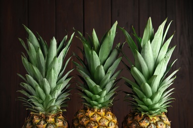 Photo of Fresh ripe juicy pineapples on wooden background