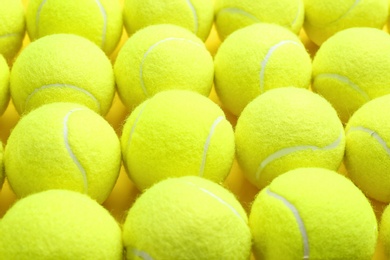Tennis balls on yellow background, closeup. Sports equipment