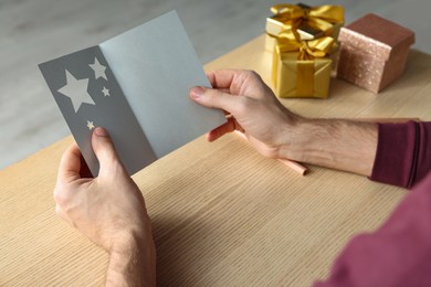 Photo of Man holding greeting card at wooden table, closeup