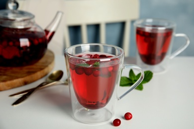 Tasty hot cranberry tea with mint and fresh berries on light table