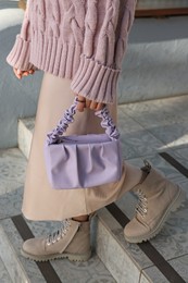 Fashionable woman with stylish bag on stairs outdoors, closeup