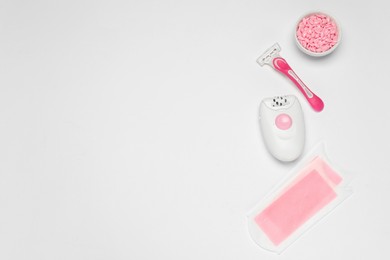 Flat lay composition with epilator and other hair removal products on white background. Space for text