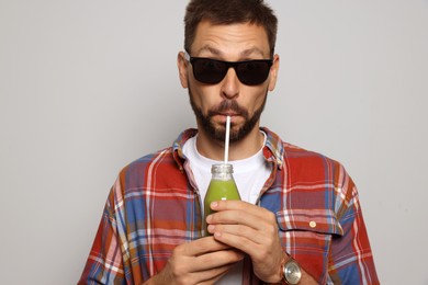 Photo of Man drinking delicious juice on grey background