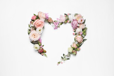 Beautiful heart made of different flowers on white background, top view