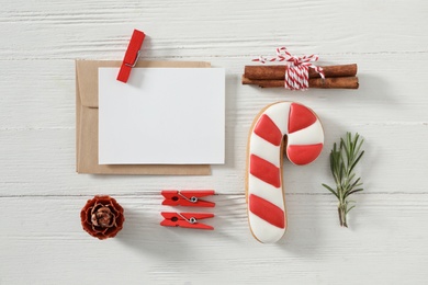 Flat lay composition with blank greeting card and Christmas cookie on white wooden table, space for text