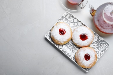 Hanukkah food doughnuts with jelly and sugar powder served on grey table, flat lay. Space for text