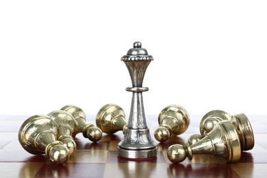 Silver queen among fallen golden pawns on wooden chess board against white background